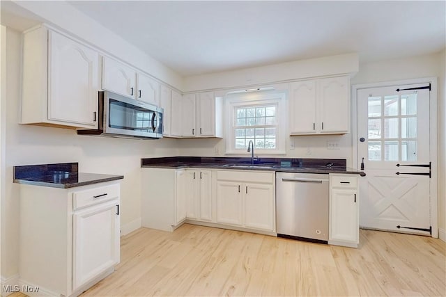 kitchen with sink, white cabinets, appliances with stainless steel finishes, and light wood-type flooring