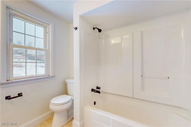 bathroom with hardwood / wood-style floors, toilet, and bathing tub / shower combination