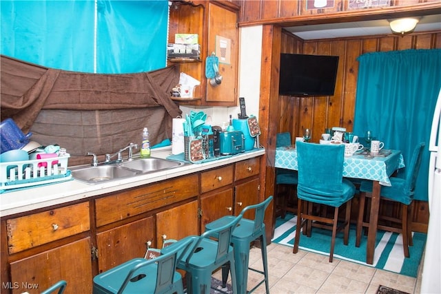 kitchen with sink, wood walls, and light tile patterned floors