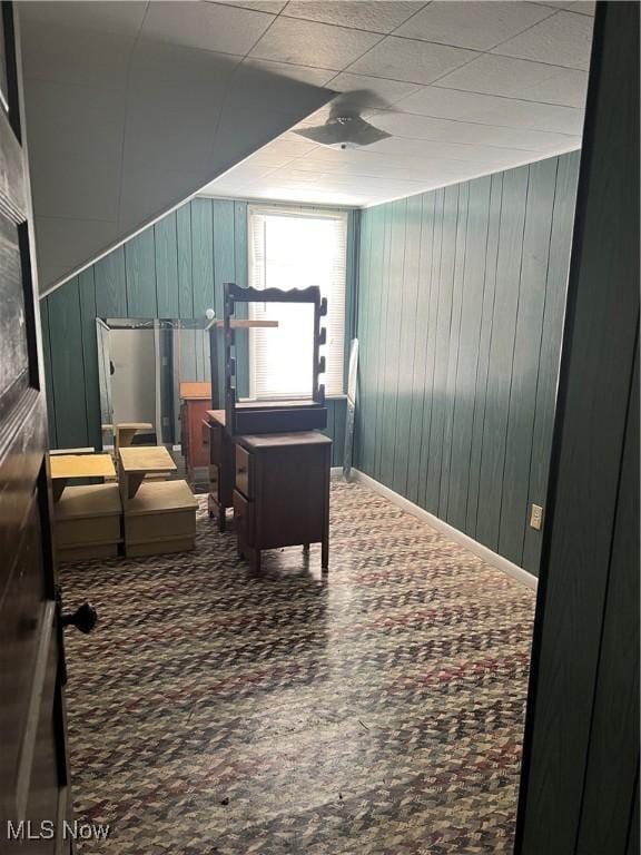 sitting room with carpet floors and wood walls