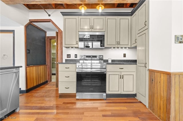 kitchen with stainless steel appliances, dark stone countertops, wood walls, light hardwood / wood-style flooring, and beam ceiling