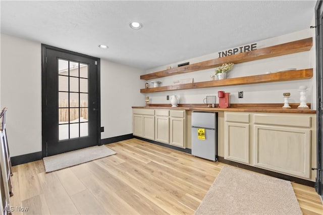 bar with light hardwood / wood-style floors, fridge, wooden counters, and cream cabinets