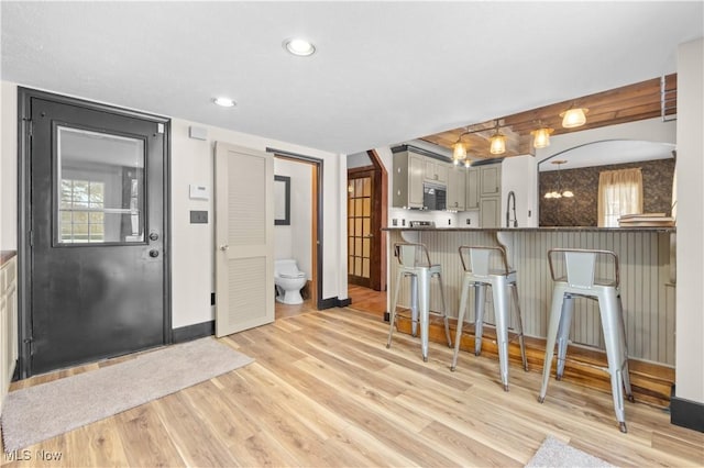 kitchen with a kitchen bar, gray cabinetry, sink, kitchen peninsula, and light hardwood / wood-style flooring