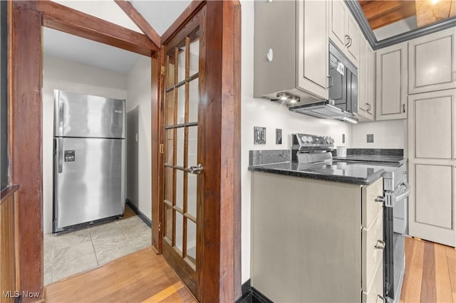 kitchen featuring dark stone countertops, stainless steel appliances, and light wood-type flooring