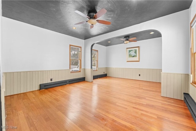 unfurnished living room featuring ceiling fan, baseboard heating, and light hardwood / wood-style flooring