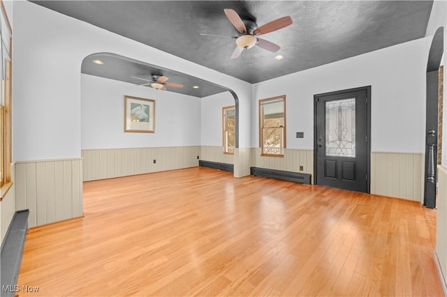 unfurnished living room with light hardwood / wood-style floors, ceiling fan, and a baseboard radiator