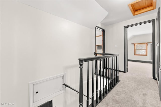 hallway with light colored carpet and vaulted ceiling