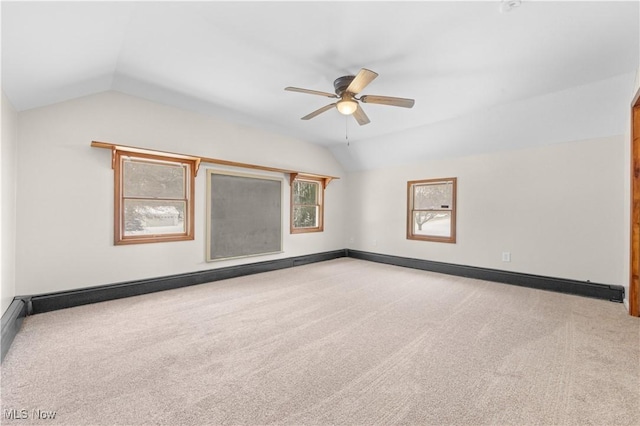 empty room featuring a baseboard radiator, carpet floors, vaulted ceiling, and ceiling fan