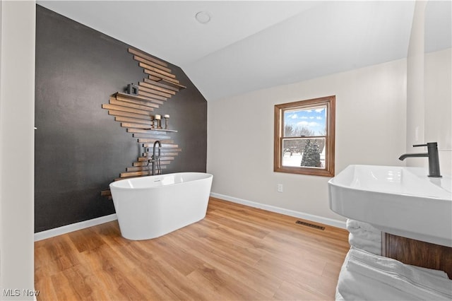 interior space featuring wood-type flooring, a bathing tub, and lofted ceiling