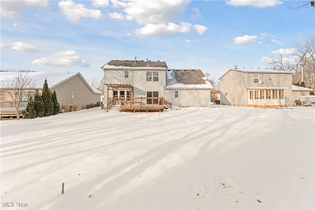 snow covered house featuring a deck and a pergola