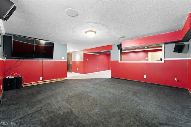 basement with dark carpet, baseboard heating, and a textured ceiling