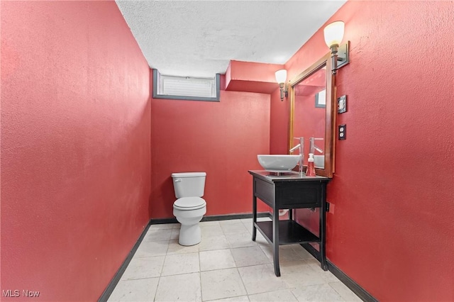 bathroom featuring a textured ceiling, toilet, and vanity