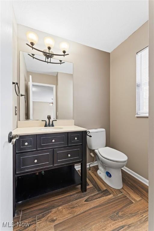 bathroom with vanity, toilet, an inviting chandelier, and parquet flooring