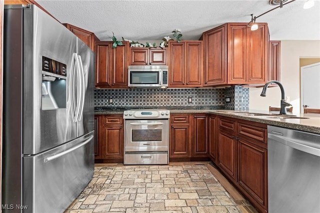 kitchen with a textured ceiling, decorative backsplash, sink, dark stone countertops, and stainless steel appliances