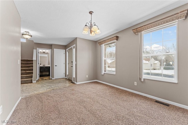 carpeted spare room with a notable chandelier