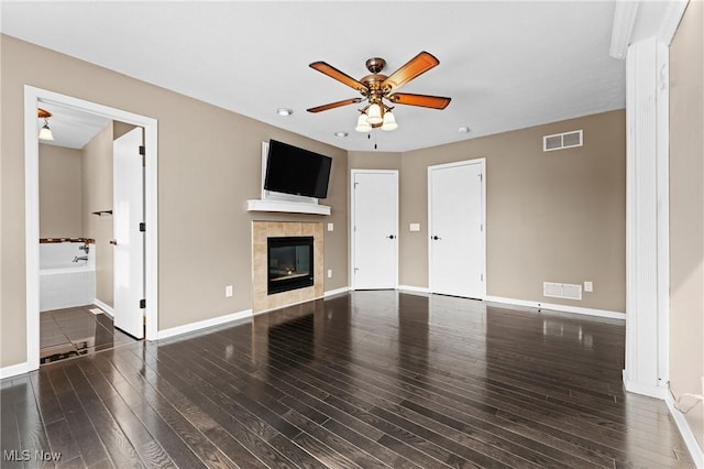 unfurnished living room with ceiling fan, dark hardwood / wood-style floors, and a tile fireplace