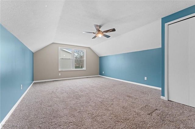 bonus room featuring carpet flooring, a textured ceiling, vaulted ceiling, and ceiling fan