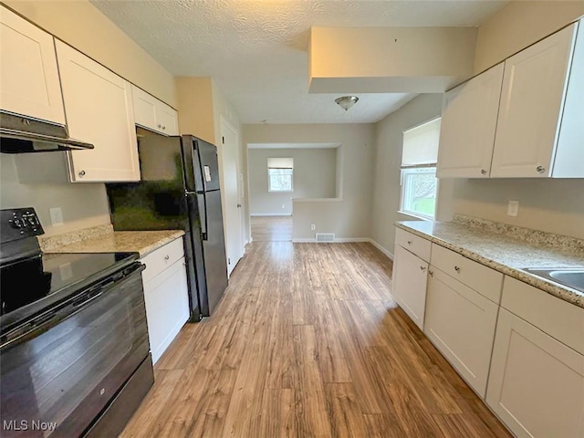 kitchen with black appliances, white cabinets, and plenty of natural light