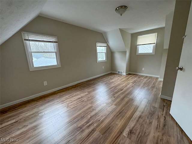 additional living space featuring hardwood / wood-style floors and vaulted ceiling