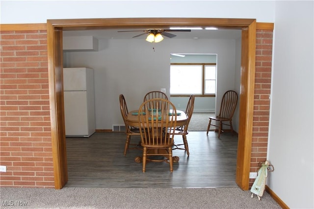 dining area with ceiling fan and dark colored carpet