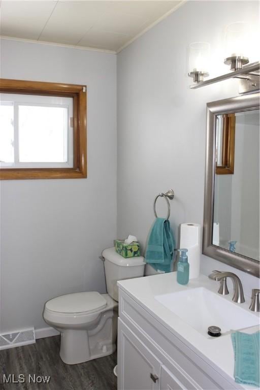 bathroom featuring hardwood / wood-style floors, toilet, vanity, and crown molding