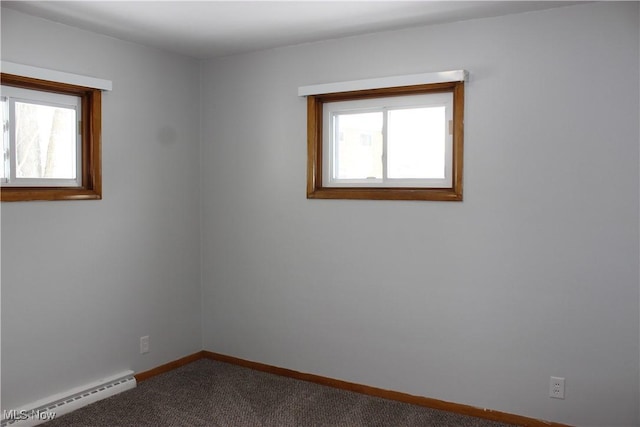 carpeted spare room with a baseboard heating unit