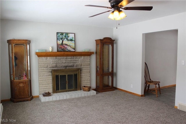 unfurnished living room featuring a stone fireplace, ceiling fan, and carpet