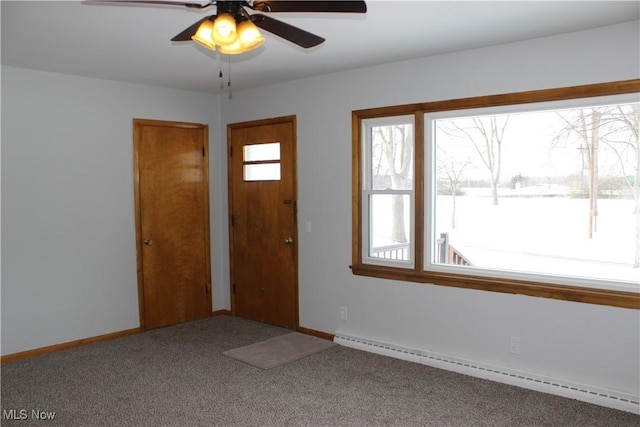 carpeted entrance foyer featuring ceiling fan, a wealth of natural light, and a baseboard heating unit