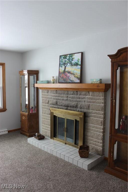 unfurnished living room with carpet flooring, baseboard heating, and a fireplace