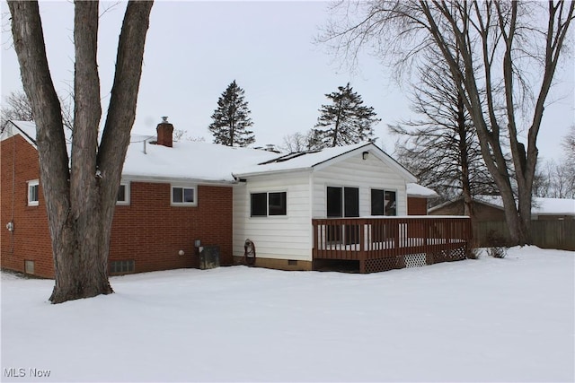 snow covered property featuring a deck, crawl space, and a chimney