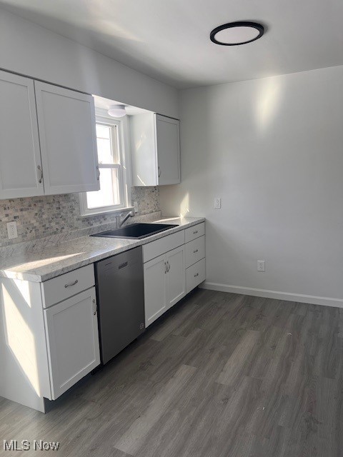 kitchen with white cabinetry, stainless steel dishwasher, sink, dark hardwood / wood-style flooring, and backsplash