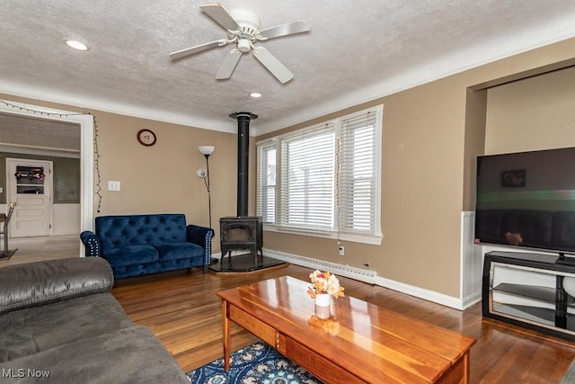 living room featuring a baseboard radiator, a textured ceiling, dark hardwood / wood-style floors, and a wood stove