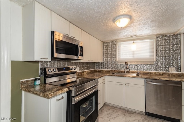 kitchen with sink, dark stone counters, white cabinetry, and appliances with stainless steel finishes