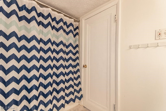 interior space with curtained shower and a textured ceiling