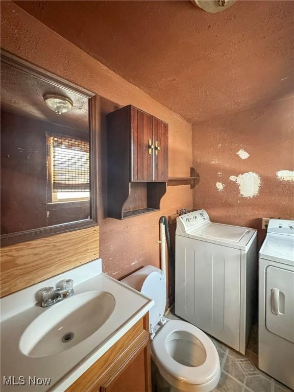 bathroom with toilet, vanity, and washing machine and clothes dryer