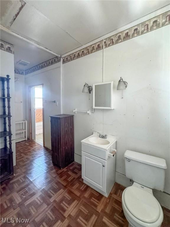 bathroom featuring vanity, toilet, and parquet flooring