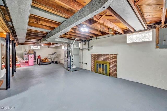 basement with a brick fireplace, electric panel, and heating unit