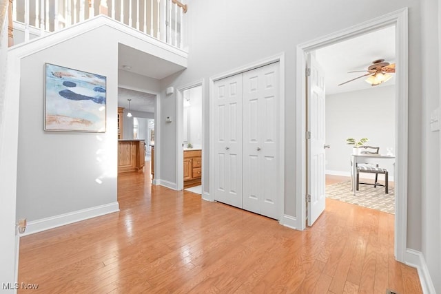 hall with a high ceiling and light hardwood / wood-style flooring