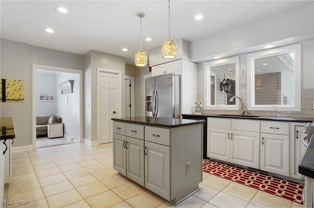 kitchen featuring a kitchen island, stainless steel refrigerator with ice dispenser, decorative light fixtures, white cabinetry, and sink