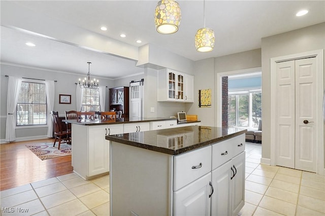 kitchen featuring white cabinets, a center island, decorative light fixtures, plenty of natural light, and light tile patterned floors