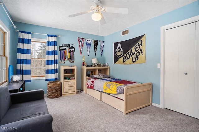 bedroom with a closet, ceiling fan, a textured ceiling, and carpet floors