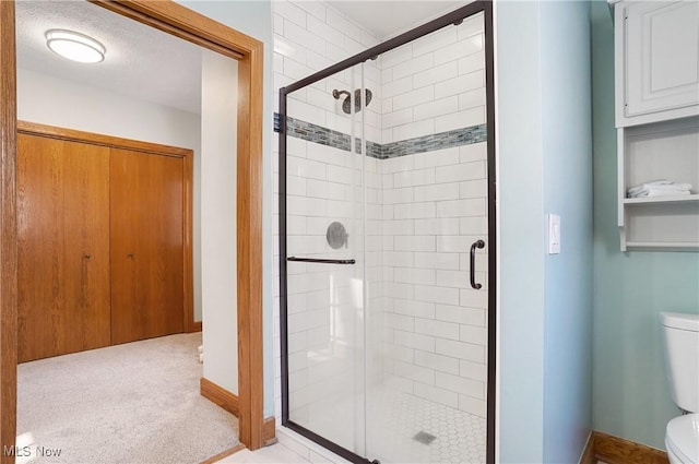 bathroom featuring a textured ceiling, toilet, and an enclosed shower