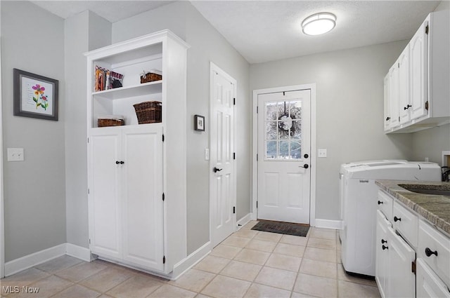 laundry room with sink, washer / clothes dryer, cabinets, and light tile patterned floors