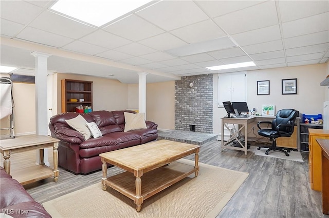 living room featuring wood-type flooring, a paneled ceiling, and decorative columns