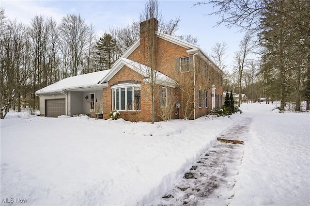 snow covered house featuring a garage