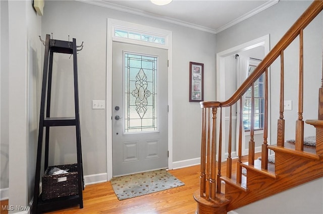 entryway with light wood-type flooring, ornamental molding, and plenty of natural light