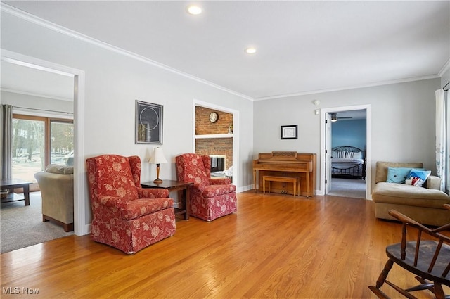 living area with hardwood / wood-style flooring, crown molding, and a fireplace