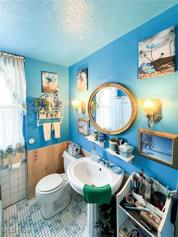 bathroom featuring sink, toilet, tile patterned floors, and a textured ceiling