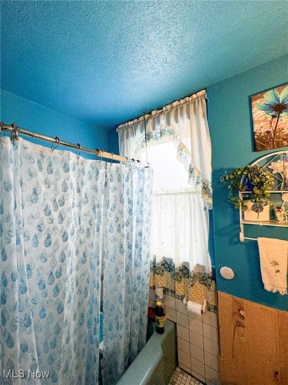 bathroom featuring tile patterned floors, a textured ceiling, and shower / tub combo with curtain