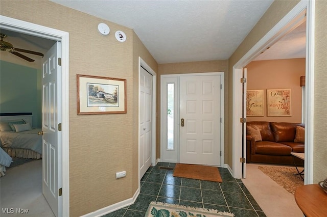 entryway with dark tile patterned flooring and ceiling fan